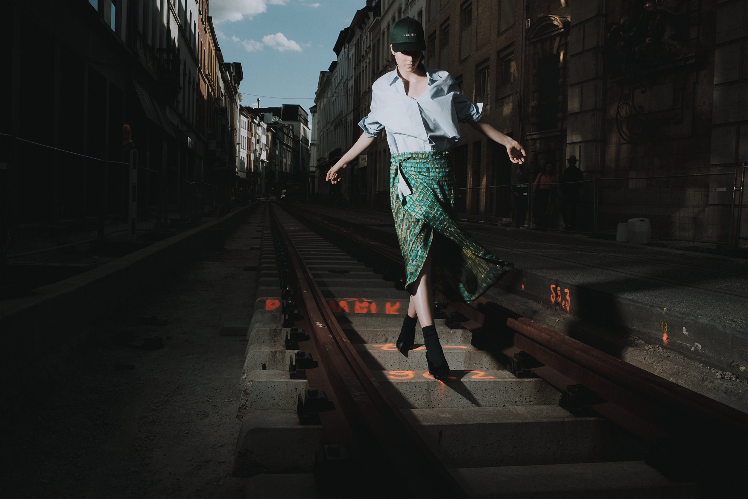 Person walking on railway tracks with a cityscape in the background