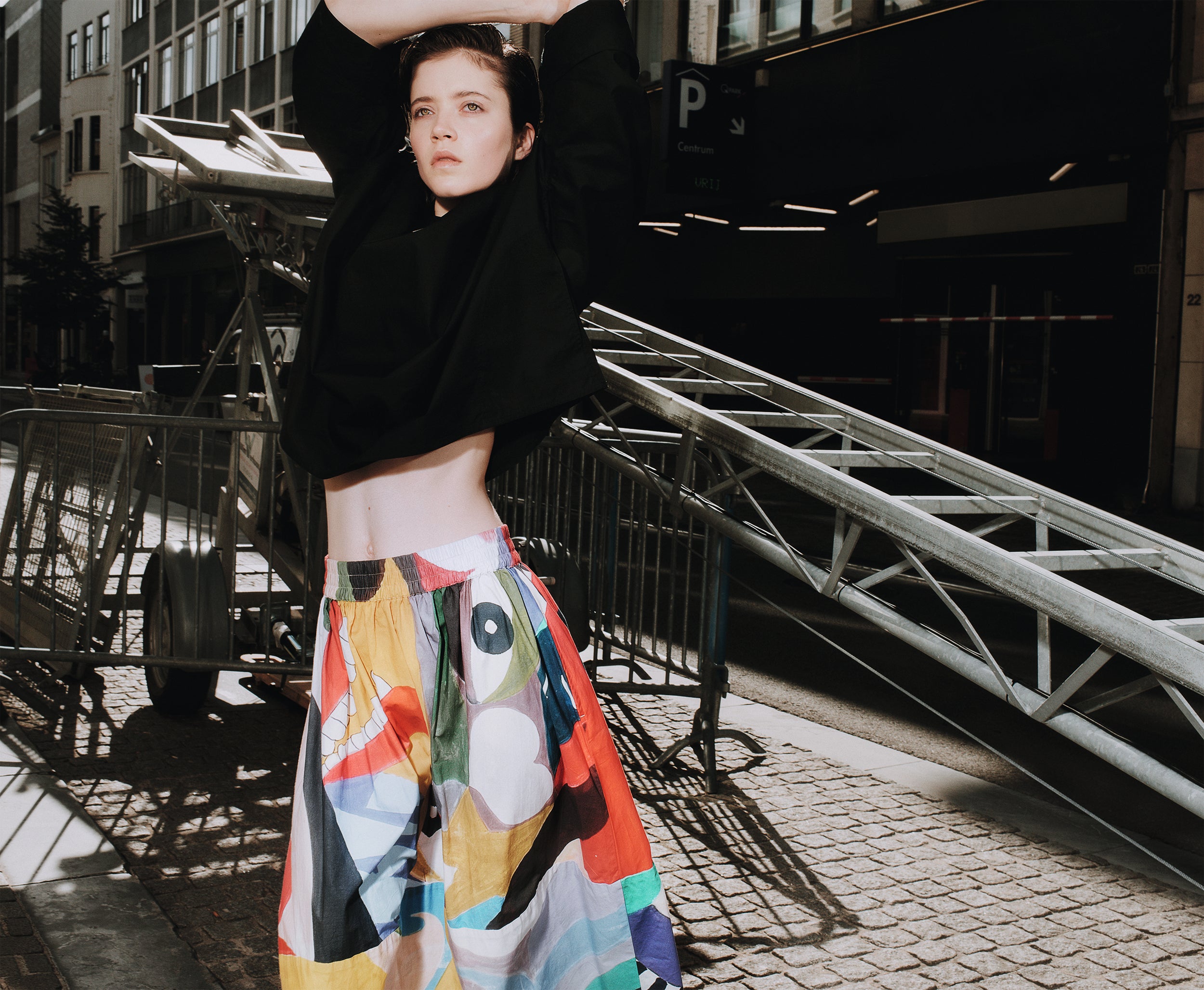 Person wearing a black top and colorful skirt in an urban setting