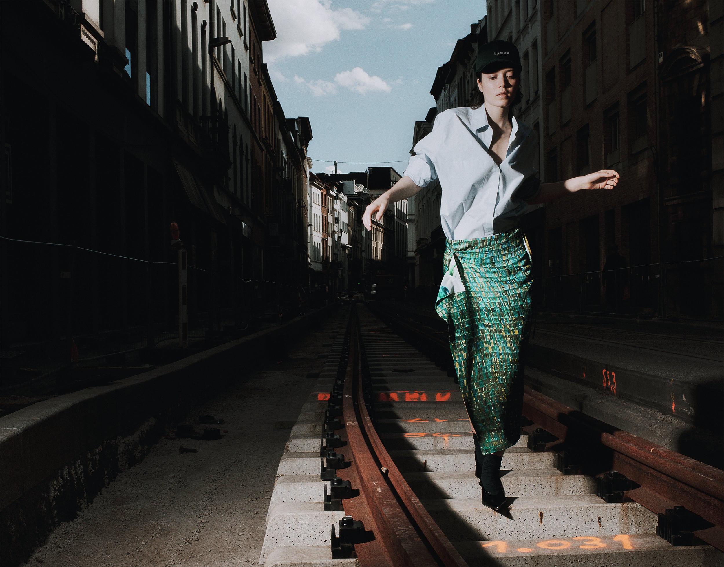 Person standing on train tracks with a cityscape background